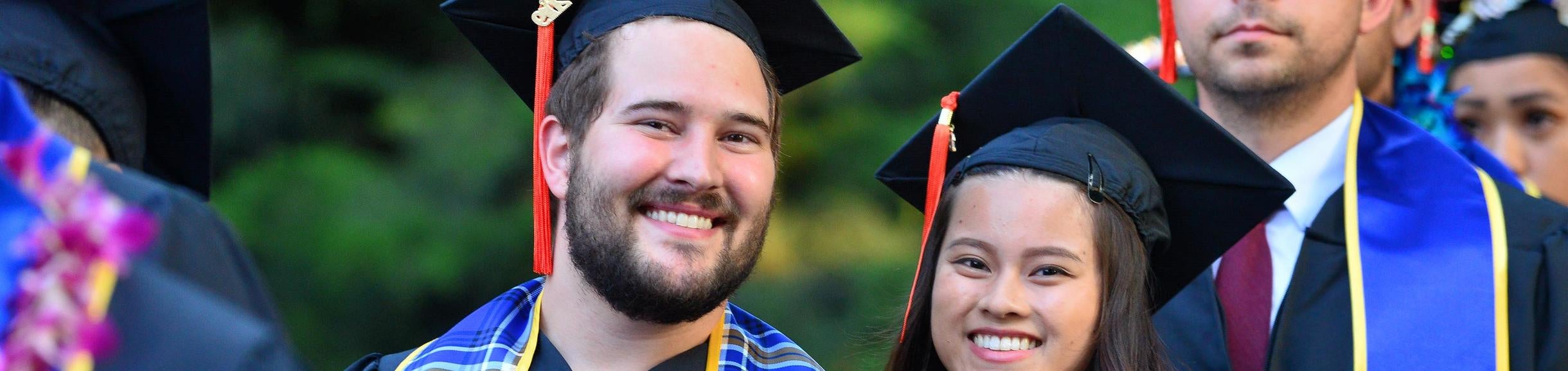 two graduates in regalia smiling